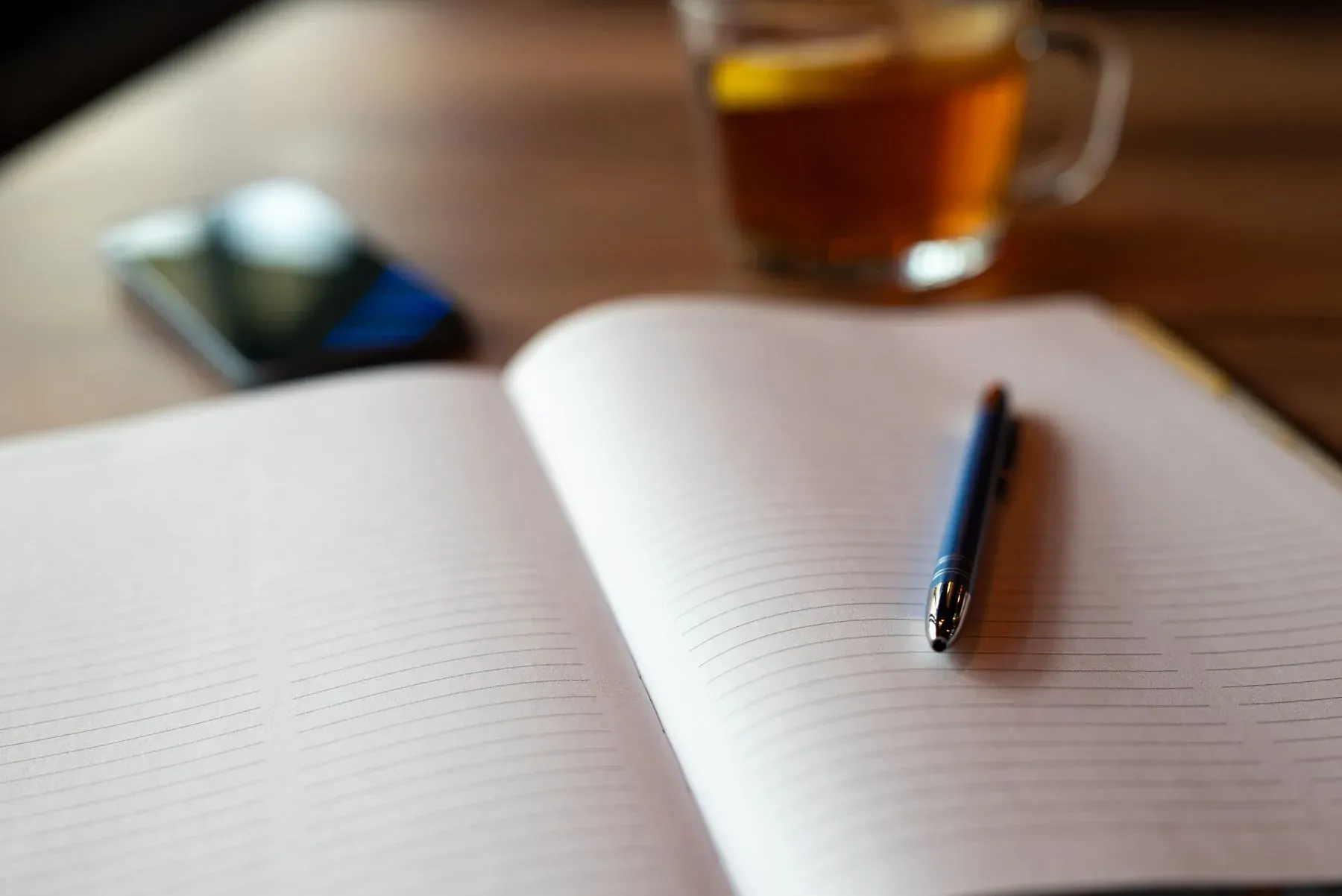 Notebook, phone and warm drink on a wooden table